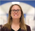 A caucasian woman stands confidently with a warm smile in the hallway of a school.
